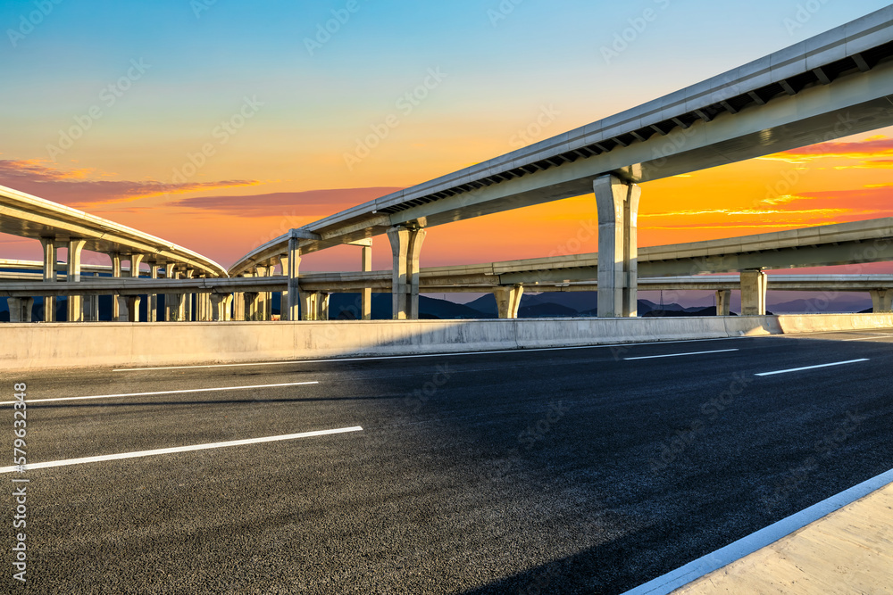 Asphalt road and urban overpass background at sunset