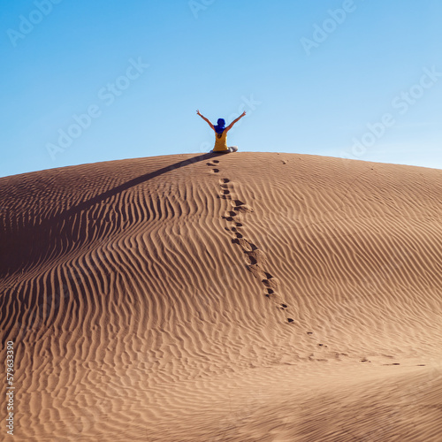 Happy woman arms raised in sand dunes desert- Sahara in Morocco