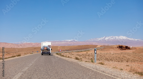 Road trip in Morocco- Asphalt road with driving motor home and mountain atlas in the background © M.studio