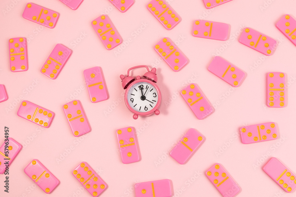 Dominoes and a pink old clock on top view,Pink background.Flat lay Dominoes and a pink old clock on top view,Pink background.Flat lay