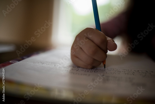 Cropped image of girl writing homework on table at home photo