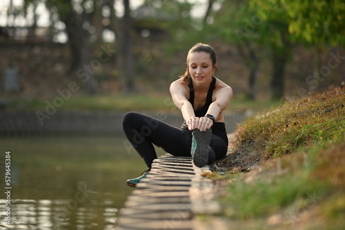 Sporty woman sporty woman stretching exercises near lake. Healthy lifestyle, sport and fitness concept