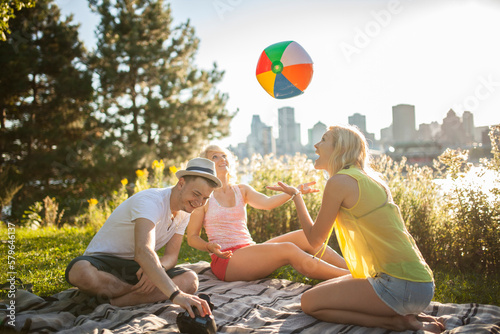 Young group of friends playing with beach ball in park during summer photo