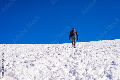 ear view of woman walking on snow covered field against sky photo