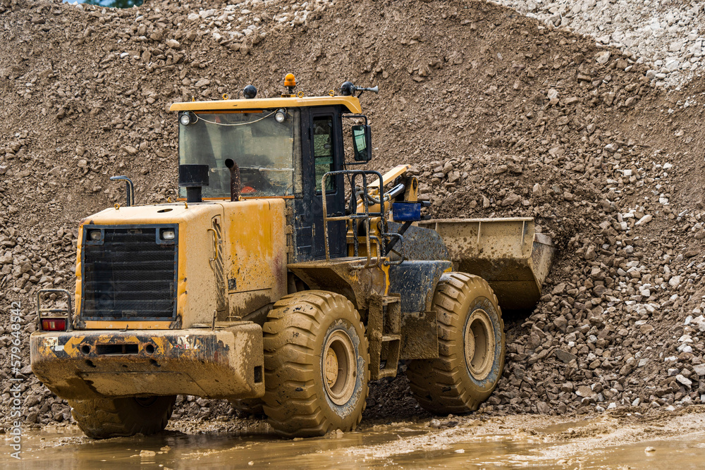 Front end loader dumping stone and sand in a mining quarry