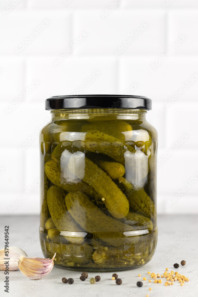 Pickled cucumbers and spices in a glass jar on a white background. Preserved pickled or salted cucumbers. Pickled cucumbers and spices in a glass jar on a white background. Preserved pickled or salted cucumbers.