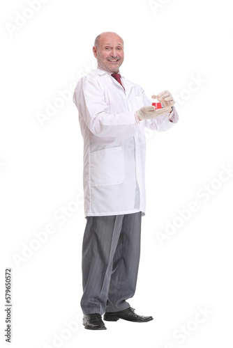 Mature scientist with grey hair and beard in white coat standing with beaker in his hand and holding medical test
