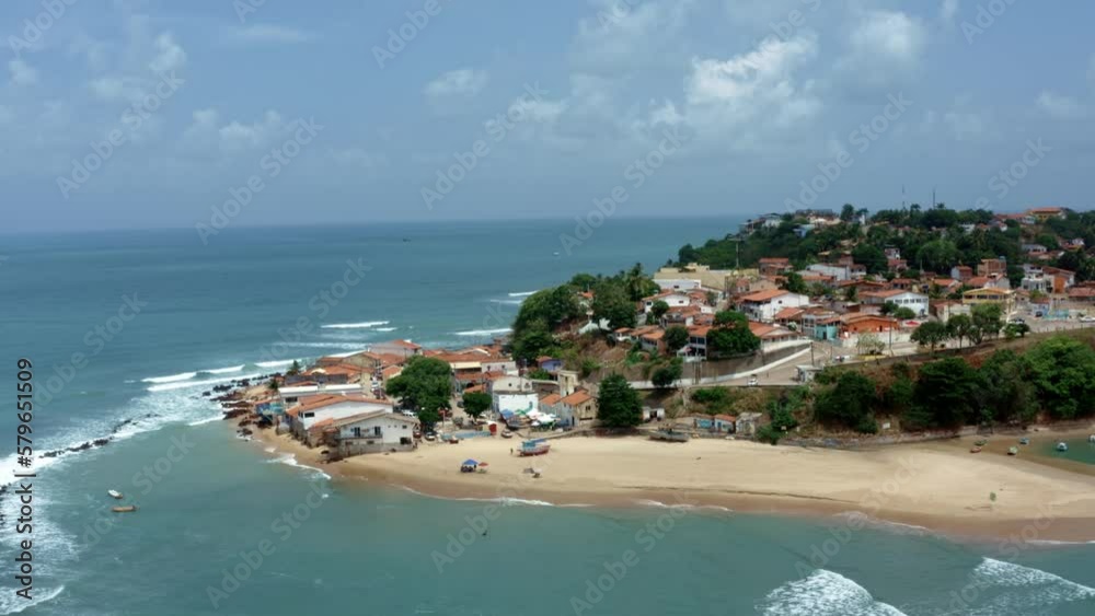 Dolly out rotating aerial drone wide shot of the tropical famous Baia Formosa beach town in the state of Rio Grande do Norte, Brazil with fishing boats, coastal homes, small waves, and surfers. Dolly out rotating aerial drone wide shot of the tropical famous Baia Formosa beach town in the state of Rio Grande do Norte, Brazil with fishing boats, coastal homes, small waves, and surfers.