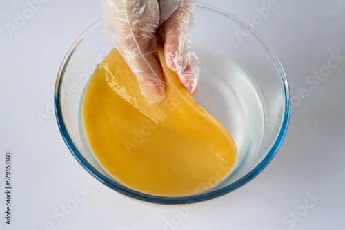 Woman puts a scoby or fungus in a glass bowl of water to wash the tea mushroom for fermentation. Preparing a healthy kombucha drink. photo