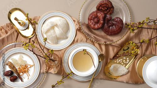 Many types of herb, lingzhi mushroom, jujube, cordyceps and ginseng displayed with edible bird’s nest and bird’s nest soup on a golden tablecloth. Combination brings many benefits for health and skin photo