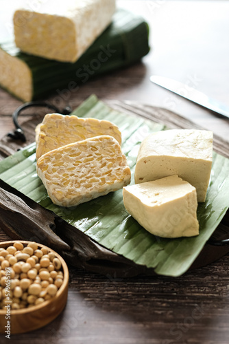 raw tempeh and tofu on a cutting board.  tempeh and tofu made from soybeans seed.