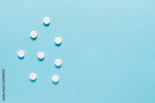 Scattered white pills on blue background. Mock up for special offers as advertising, web background or other ideas. Medical, pharmacy and healthcare concept. copyspace. Empty place for text or logo