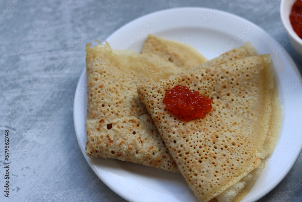 Tiny crepes on a plate. Crepes with salmon caviar. Savory food close up photo. Traditional French pancakes. Tiny crepes on a plate. Crepes with salmon caviar. Savory food close up photo. Traditional French pancakes.