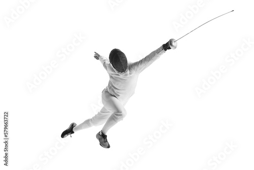 Full-length portrait of sportive man, professional fencer in fencing costume and protective helmet mask in motion isolated on white studio background.