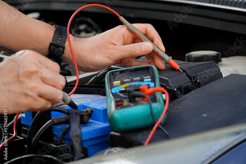 technician checks the battery using a voltmeter capacity tester,auto mechanic uses a multimeter voltmeter to check the voltage level in a car battery