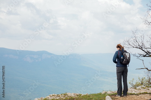 a woman stands on a mountain and looks far away nature hiking journey
