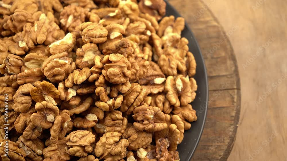 Nuts in a bowl. Healthy food top view. Nut without shell on a plate. Whole and half walnuts kernels. Peeled walnut.