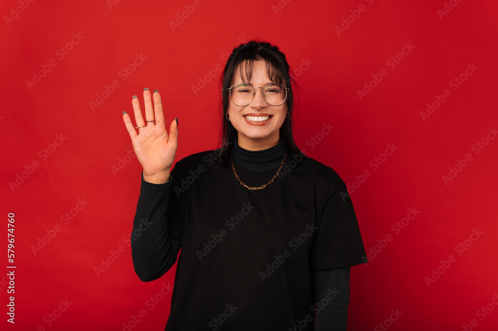 Cute smiling woman is waving and saying hi to you over red background. Cute smiling woman is waving and saying hi to you over red background.