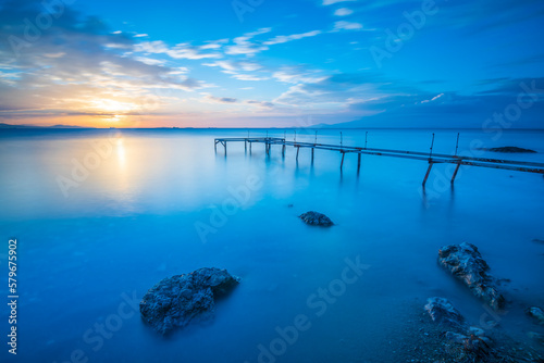 Iron made pier on sunset with beautiful colorful clouds and silky smooth sea water with long exposure photography technic