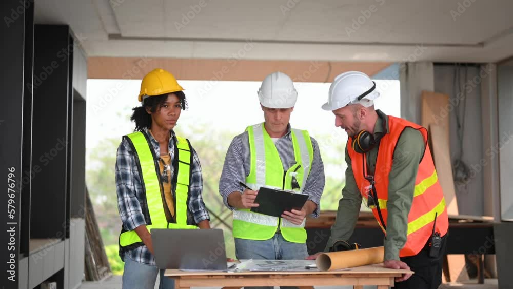Contractor and architect looking at plan, tablet, laptop and talking about working on big project. Building in construction process interior... Contractor and architect looking at plan, tablet, laptop and talking about working on big project. Building in construction process interior...