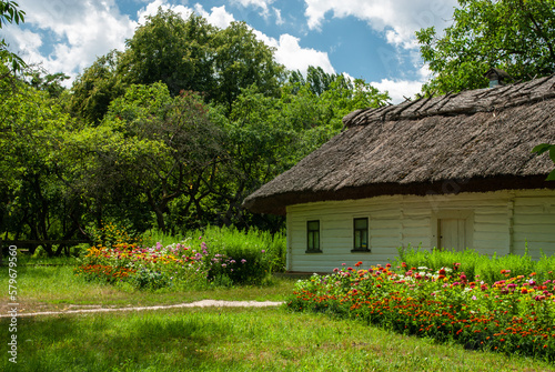 Old ancient ukrainian village house with flowers, nature at summer time, Ukraine traditions and history