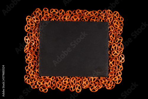 Rectangular frame of mini pretzels on black background. Dark backdrop with Oven-baked crisps