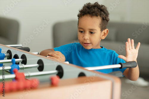  An African boy is having fun playing table football in a children's play entertainment center. Hobby and leisure