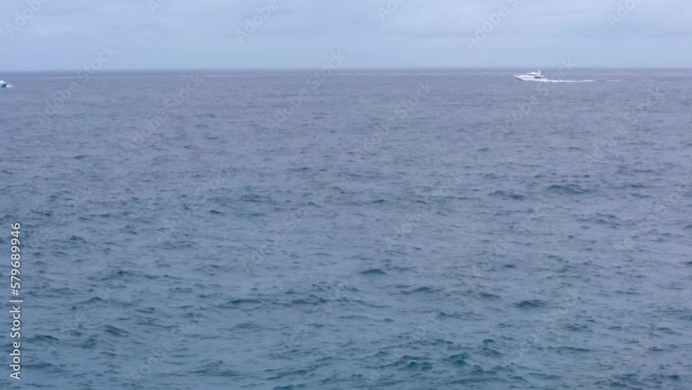 Wide view of dolphins in wavy water and distant motorboats, Indonesia Wide view of dolphins in wavy water and distant motorboats, Indonesia