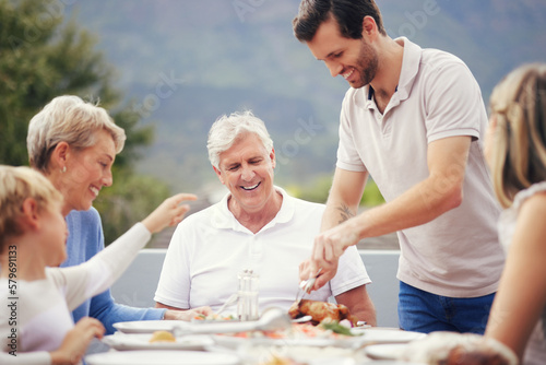 Family eating lunch outdoor garden for holiday celebration  fathers day or thanksgiving turkey food. Happy  care and love people with grandparents and child brunch together in garden to celebrate dad