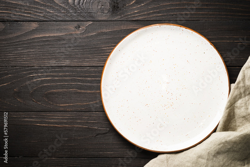 White craft plate at dark wooden table. Top view image with copy space.