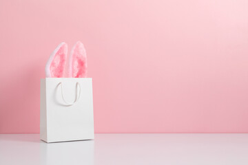 Easter market background. Gift bag with bunny on pink table background. Concept of online shopping for Easter, design, texture. Front view