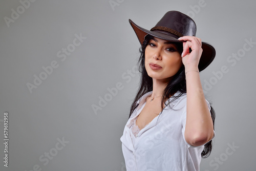 a beautiful brunette woman in a casual outfit with a hat in the studio