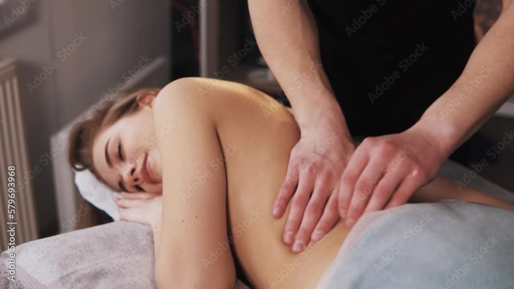 Close-up of male hands giving massage to a young woman's back on a massage table Close-up of male hands giving massage to a young woman's back on a massage table