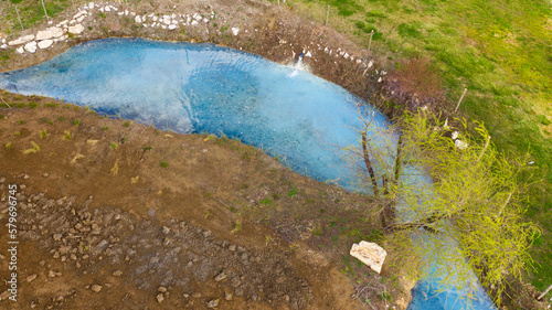 Aerial view on a small stream flowing in the middle of the countryside. The river is clear blue and there is nobody on its banks.