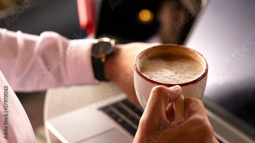closeup of a man's hand holding a cup of coffee and looking at the time with the other hand