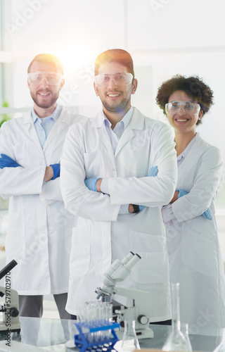 Smiling scientists looking at camera arms crossed in laboratory
