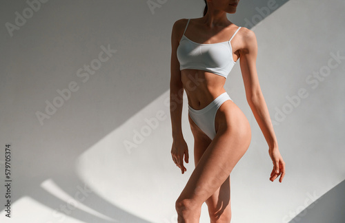 Beautiful shadows from sunlight. Young caucasian woman with slim body shape is indoors in the studio