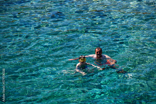 Father and son swimming in the blue sea 