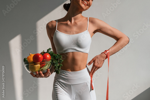 Conception of diet. With vegetalbes and fruits. Young caucasian woman with slim body shape is indoors in the studio photo