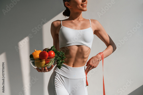 Conception of diet. With vegetalbes and fruits. Young caucasian woman with slim body shape is indoors in the studio photo