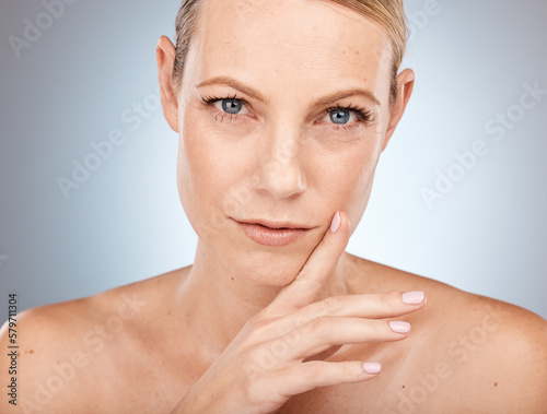 Mature woman, beauty and portrait of natural cosmetics, anti aging skincare or facial glow on studio background. Serious model touching face for dermatology, chemical peel or aesthetic transformation photo