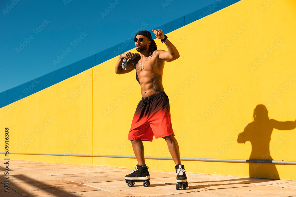 Black man on roller skates riding outside. Urban man posing with roller skates..