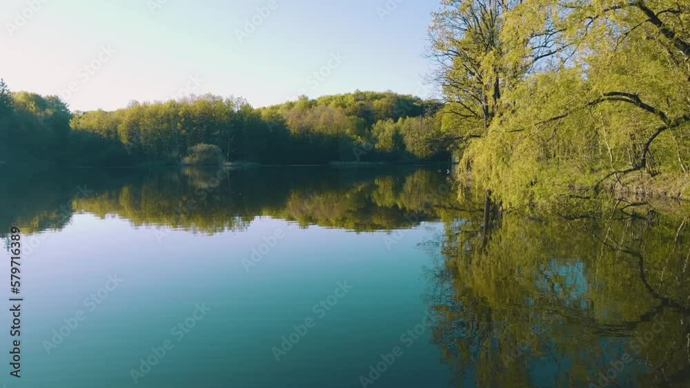 Trees and an old yellow house are reflected in the pond. Warm day in early spring Trees and an old yellow house are reflected in the pond. Warm day in early spring