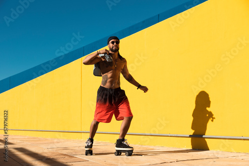 Black man on roller skates riding outside. Urban man posing with roller skates..