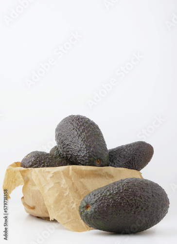 Tropical fruit, avocados on the table next to a kraft paper bag. Vertical shot.