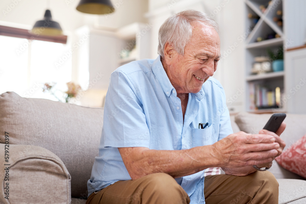 Would you look at that...Shot of an elderly man looking happy while using his smartphone at home on the sofa. Would you look at that...Shot of an elderly man looking happy while using his smartphone at home on the sofa.