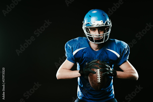 Portrait of a man in a blue uniform for american football on a black background.  © Михаил Решетников