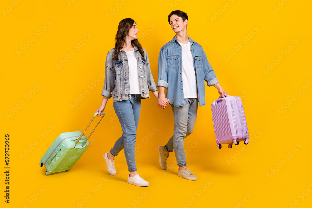 Photo of excited funny married couple wear jeans holding hands going new journey isolated yellow color background - obrazy, fototapety, plakaty 