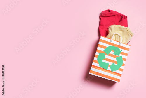 Children's clothes in shopping bag with a recycling symbol. Second hand, donation clothing recycling concept photo