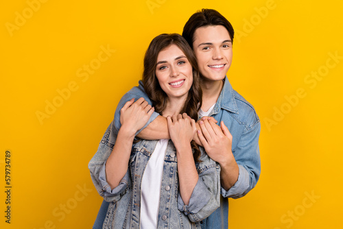 Photo of two attractive idyllic young people cuddle toothy smile isolated on yellow color background